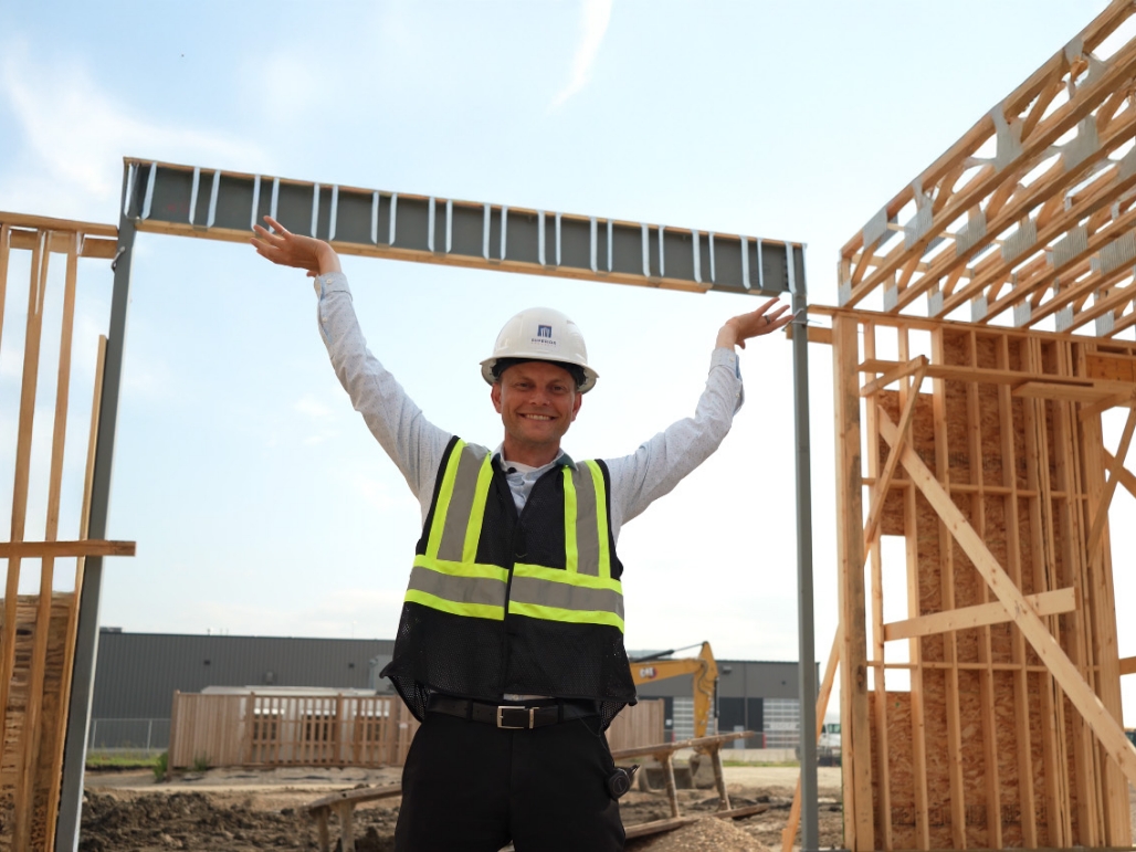 Superior Projects team member demonstrating framing progress at Manitoba commercial construction site